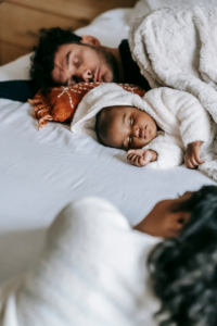 Father sleeps in bed with baby