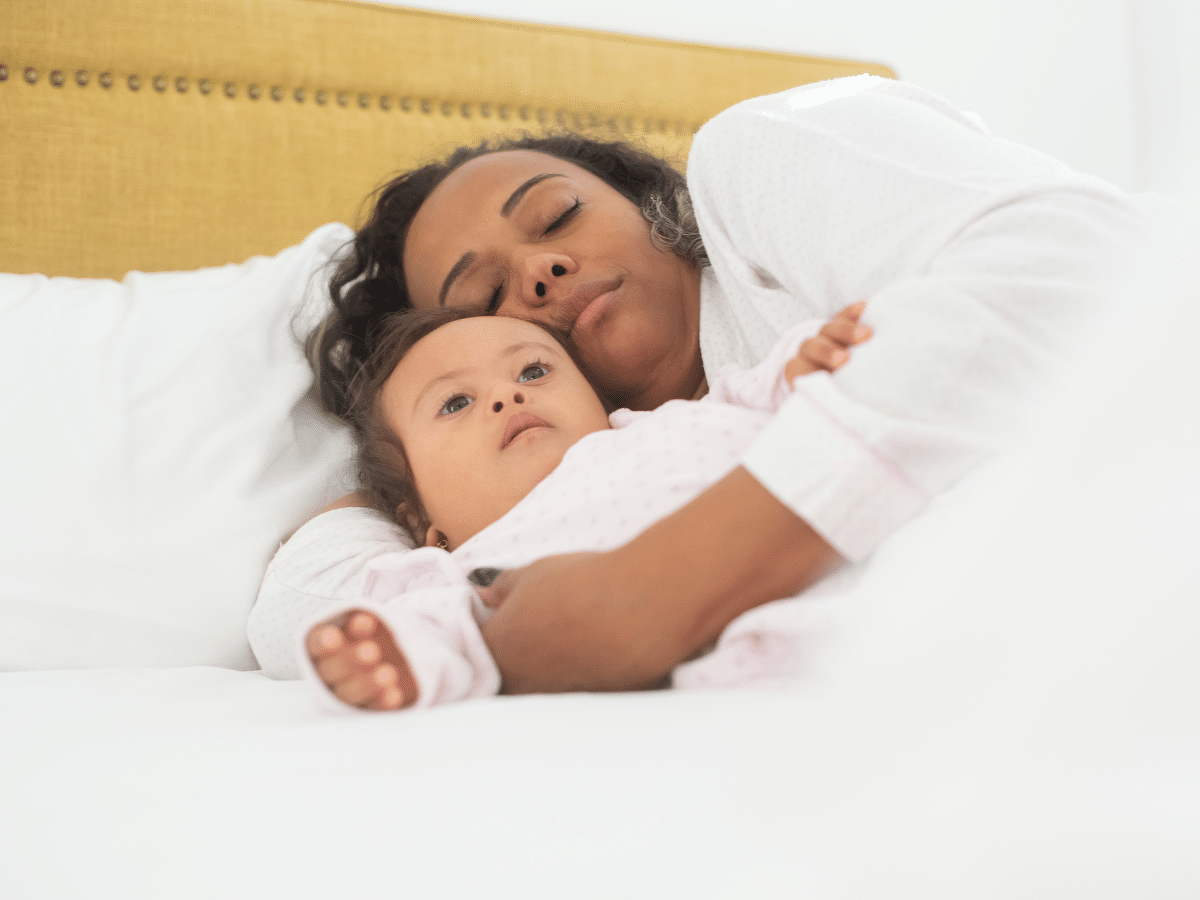 Mother cuddles with baby in bed